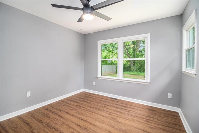 spare room featuring baseboards, wood finished floors, and a healthy amount of sunlight