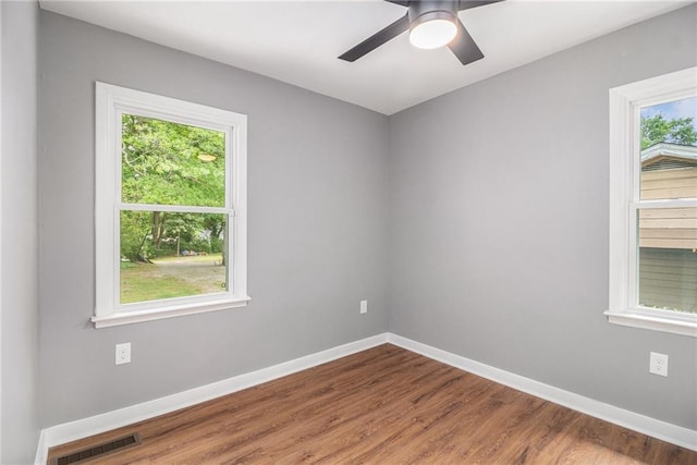 unfurnished room featuring baseboards, ceiling fan, wood finished floors, and visible vents