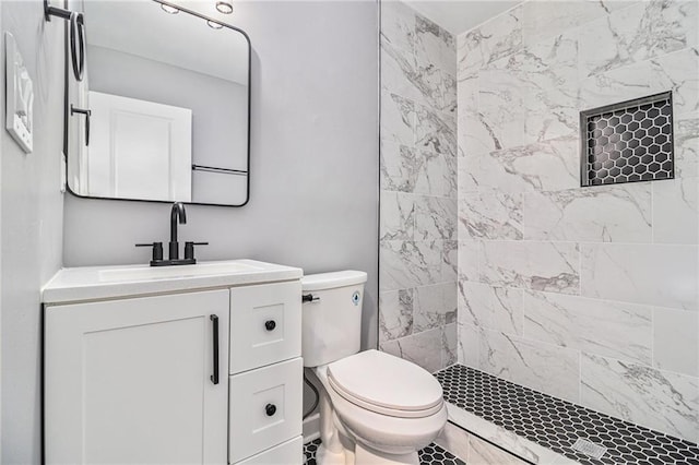 bathroom with vanity, a tile shower, and toilet