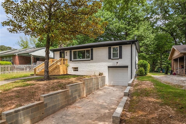 view of front facade featuring a garage, fence, driveway, and brick siding