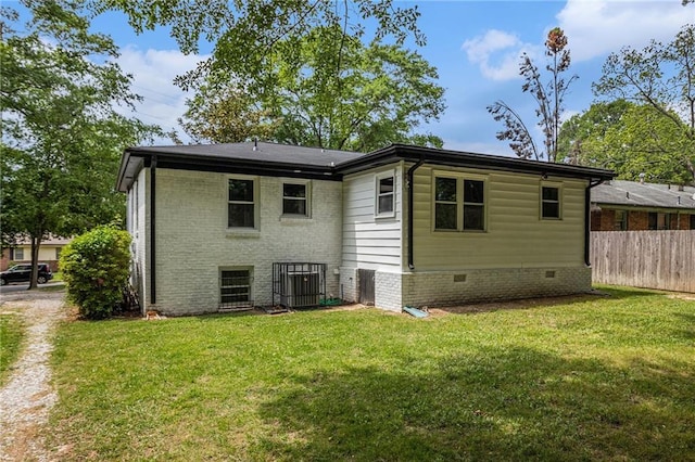 rear view of property featuring a lawn, central AC, and fence