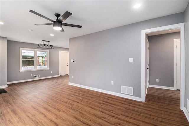spare room with baseboards, ceiling fan, wood finished floors, and visible vents