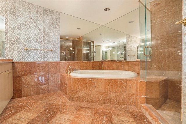 bathroom with plus walk in shower, tile walls, and vanity