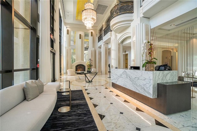 reception area featuring an inviting chandelier, ornate columns, and a fireplace