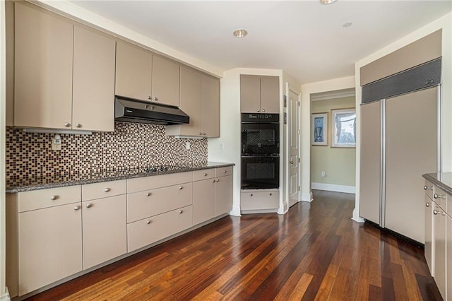 kitchen with black appliances, backsplash, dark hardwood / wood-style floors, and dark stone counters