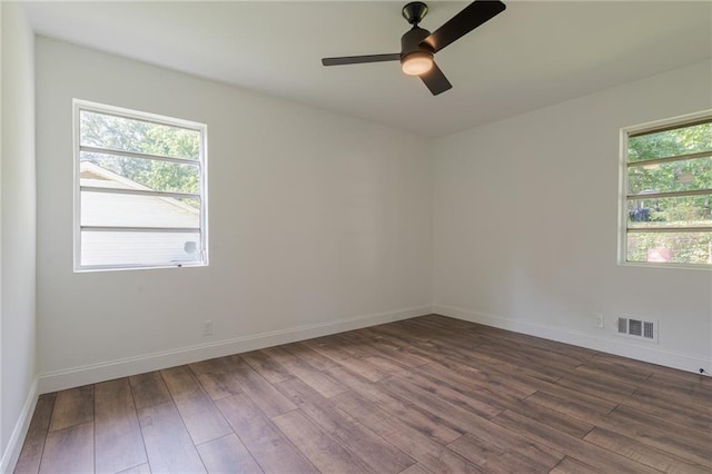 empty room with dark hardwood / wood-style flooring, plenty of natural light, and ceiling fan