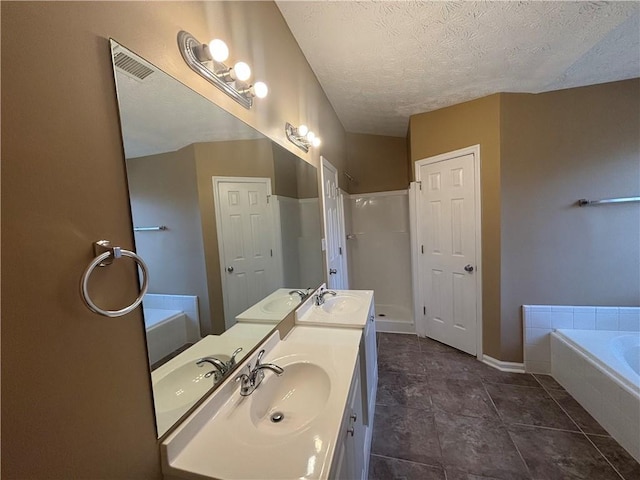 bathroom with vanity, tiled tub, and a textured ceiling