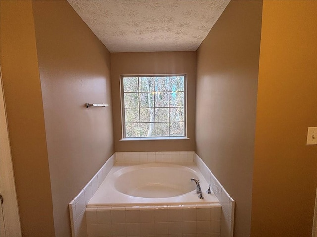 bathroom featuring tiled bath and a textured ceiling