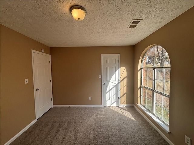 carpeted empty room featuring a textured ceiling