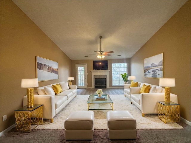 living room with lofted ceiling, a tiled fireplace, and ceiling fan