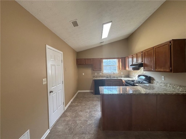 kitchen with black gas range oven, lofted ceiling, sink, dark stone counters, and kitchen peninsula