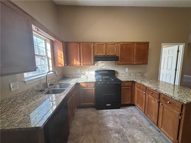 kitchen with sink, light stone counters, black gas range oven, kitchen peninsula, and a towering ceiling