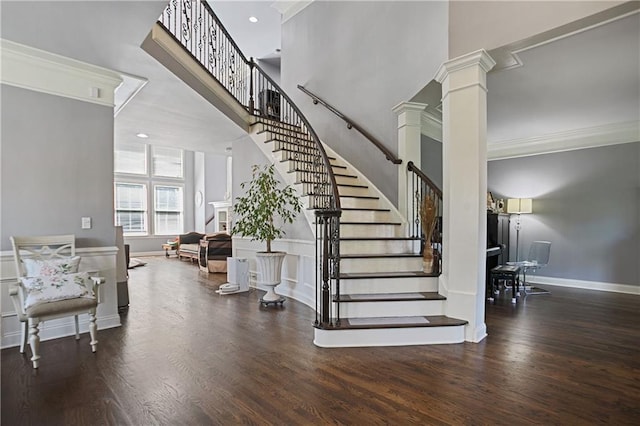 5410 Cottage Farm Rd, Alpharetta, GA 30022 - staircase featuring decorative columns, ornamental molding, a towering ceiling, wood finished floors, and a wainscoted wall