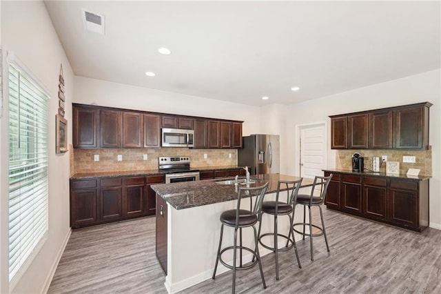 kitchen featuring sink, a kitchen breakfast bar, a kitchen island with sink, stainless steel appliances, and light hardwood / wood-style flooring