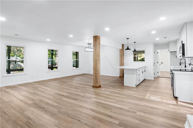 kitchen featuring decorative light fixtures, plenty of natural light, white cabinets, and light wood-type flooring