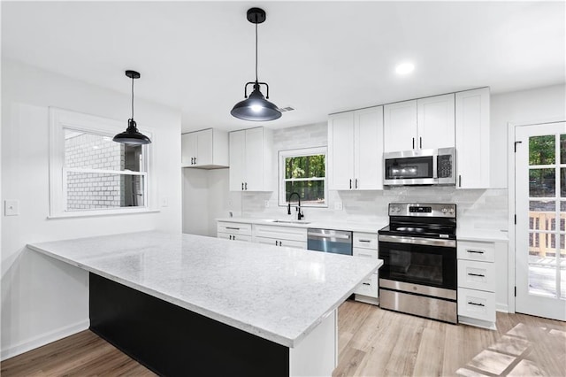 kitchen with sink, white cabinetry, kitchen peninsula, stainless steel appliances, and backsplash