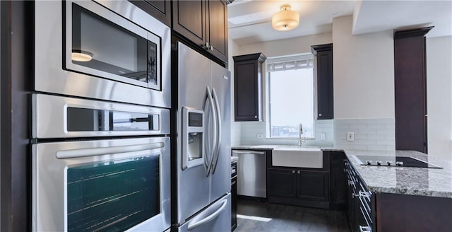 kitchen featuring stainless steel appliances, decorative backsplash, sink, light stone countertops, and dark hardwood / wood-style floors