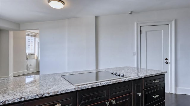 kitchen featuring black electric stovetop, light stone counters, and cooling unit