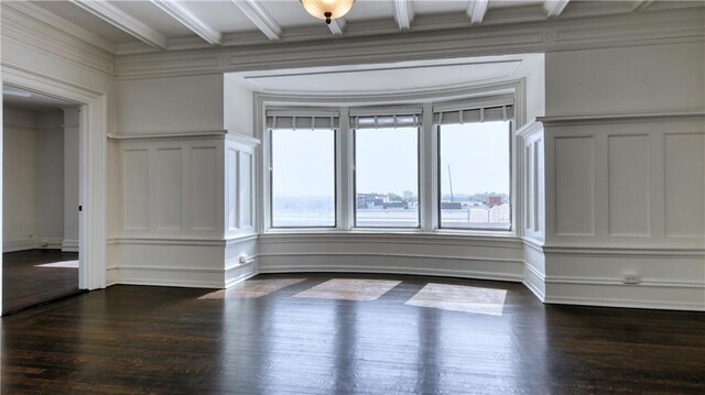 spare room featuring dark hardwood / wood-style floors, ornamental molding, and beam ceiling