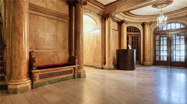 interior space with tile patterned floors, crown molding, and ornate columns