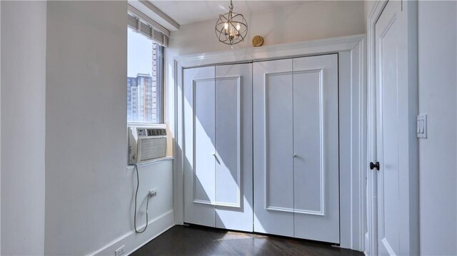 doorway featuring a notable chandelier, cooling unit, and dark wood-type flooring