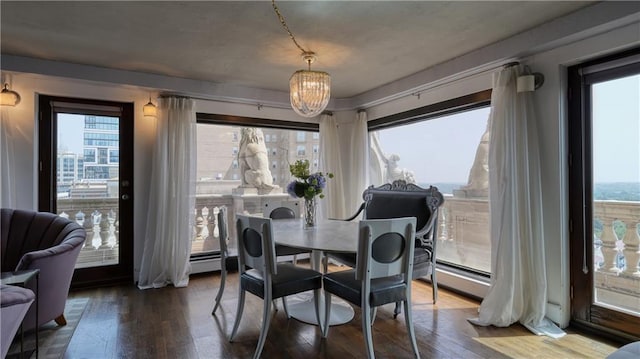 dining room with hardwood / wood-style flooring, a healthy amount of sunlight, baseboard heating, and a chandelier