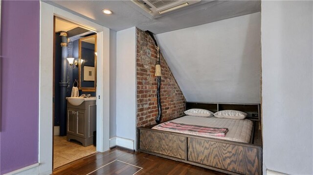 bedroom with lofted ceiling, dark hardwood / wood-style flooring, and sink