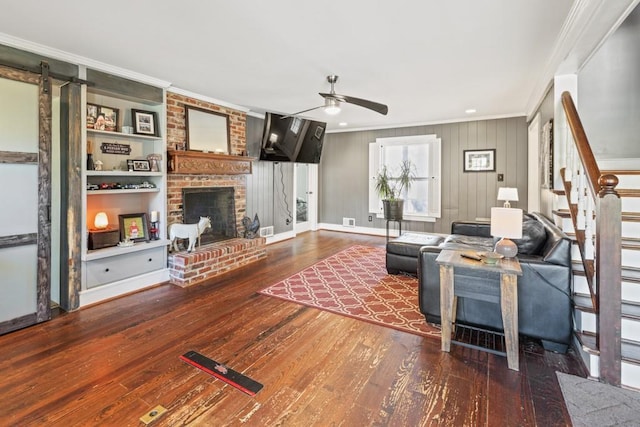 living room with a fireplace, crown molding, wood-type flooring, and ceiling fan