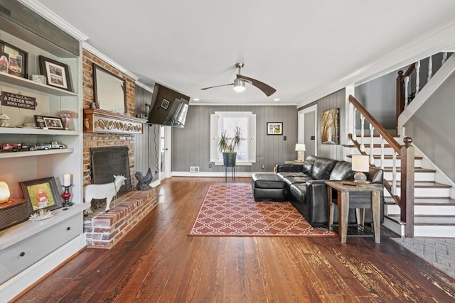 living room featuring ceiling fan, ornamental molding, dark hardwood / wood-style floors, and a brick fireplace