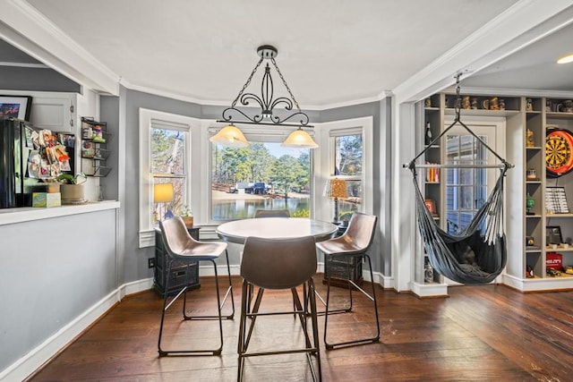 dining space with dark hardwood / wood-style flooring, crown molding, and a chandelier