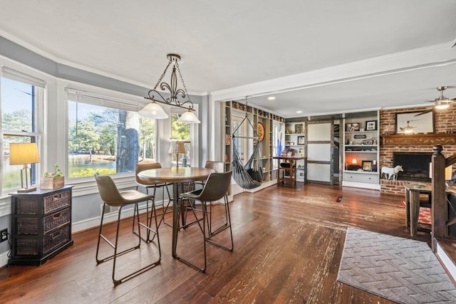 dining room with built in shelves, ceiling fan, ornamental molding, and dark hardwood / wood-style flooring