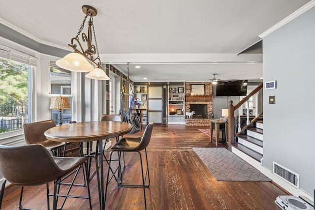 dining room featuring dark hardwood / wood-style flooring, crown molding, a fireplace, and ceiling fan