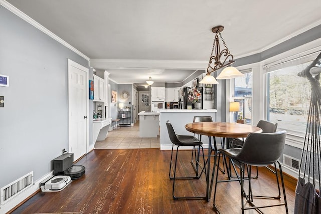 dining room with ornamental molding and light hardwood / wood-style floors