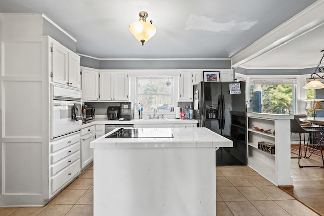 kitchen featuring hanging light fixtures, tile countertops, white cabinets, and black appliances