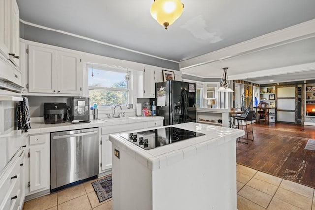 kitchen featuring white cabinetry, sink, a center island, tile counters, and black appliances