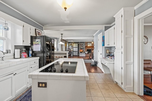 kitchen with white cabinetry, a center island, tile counters, and black appliances