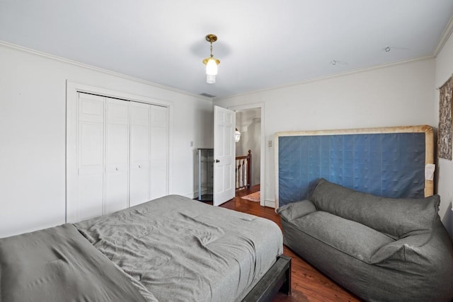 bedroom with crown molding, dark wood-type flooring, and a closet