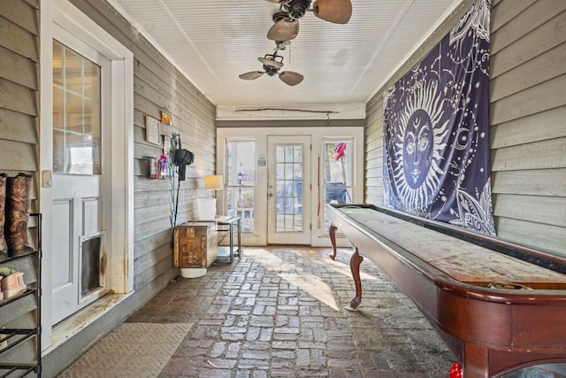 interior space featuring ceiling fan and wooden walls