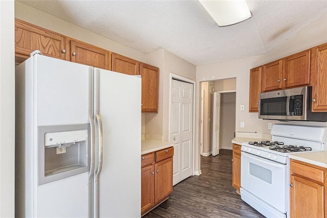 kitchen with a textured ceiling, dark hardwood / wood-style floors, and white appliances