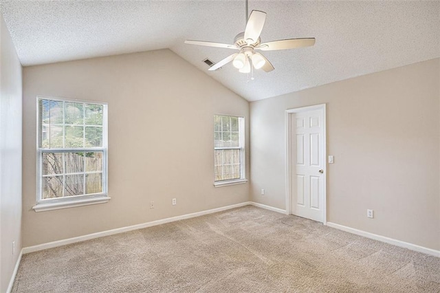 carpeted spare room featuring lofted ceiling, ceiling fan, and a textured ceiling