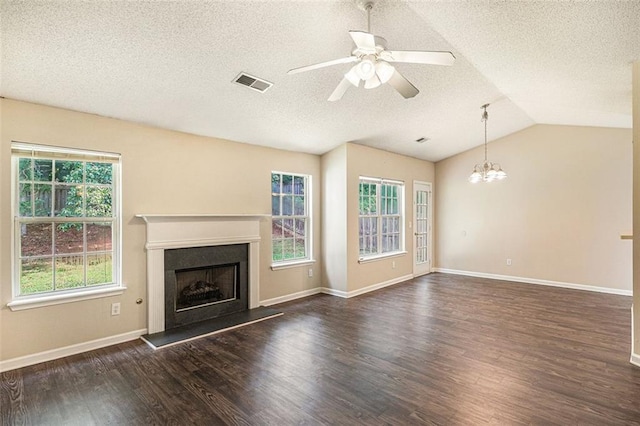 unfurnished living room featuring vaulted ceiling, ceiling fan with notable chandelier, dark wood-type flooring, and a wealth of natural light