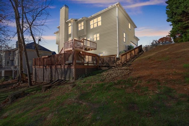 back house at dusk with a wooden deck