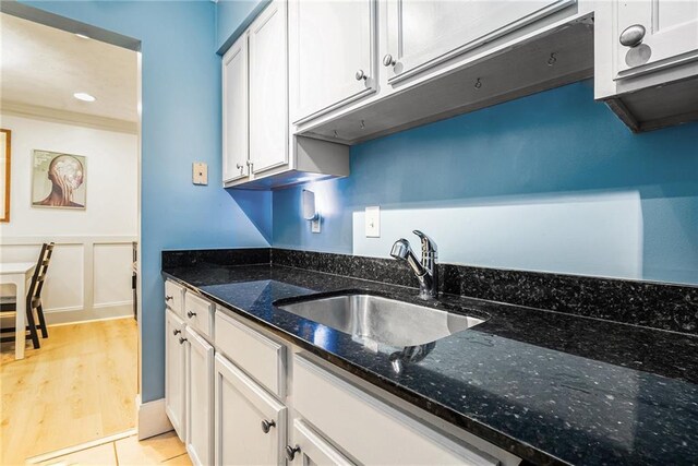 kitchen featuring sink, white cabinetry, light tile patterned floors, and dark stone countertops