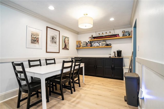 dining area with light wood-type flooring, bar, and crown molding