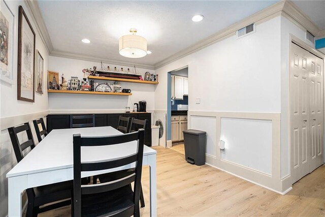 dining room featuring crown molding, light hardwood / wood-style flooring, and beverage cooler