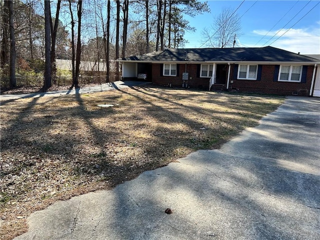 ranch-style house featuring driveway, brick siding, fence, and an attached carport