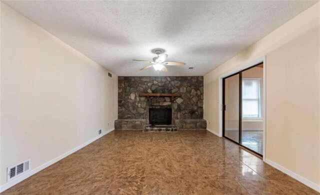 unfurnished living room featuring a textured ceiling, visible vents, a fireplace, ceiling fan, and baseboards