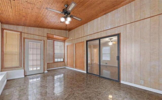 empty room featuring wood ceiling, wood walls, baseboards, and ceiling fan