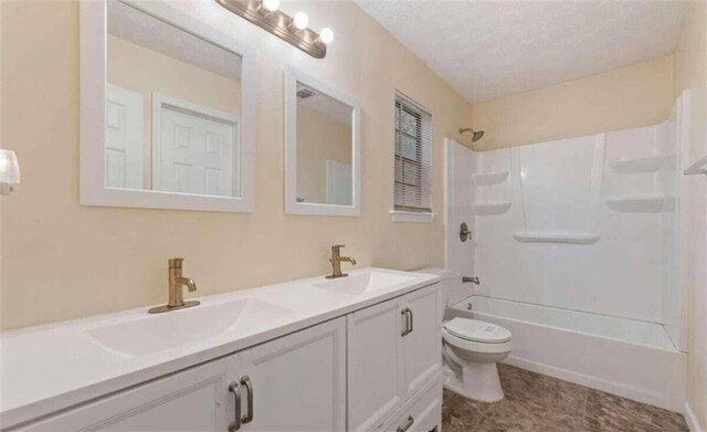 bathroom featuring double vanity, toilet, a textured ceiling, and a sink