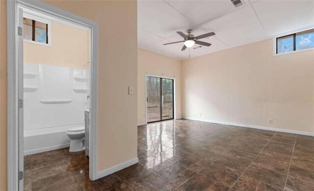 spare room with a wealth of natural light, visible vents, baseboards, and a ceiling fan